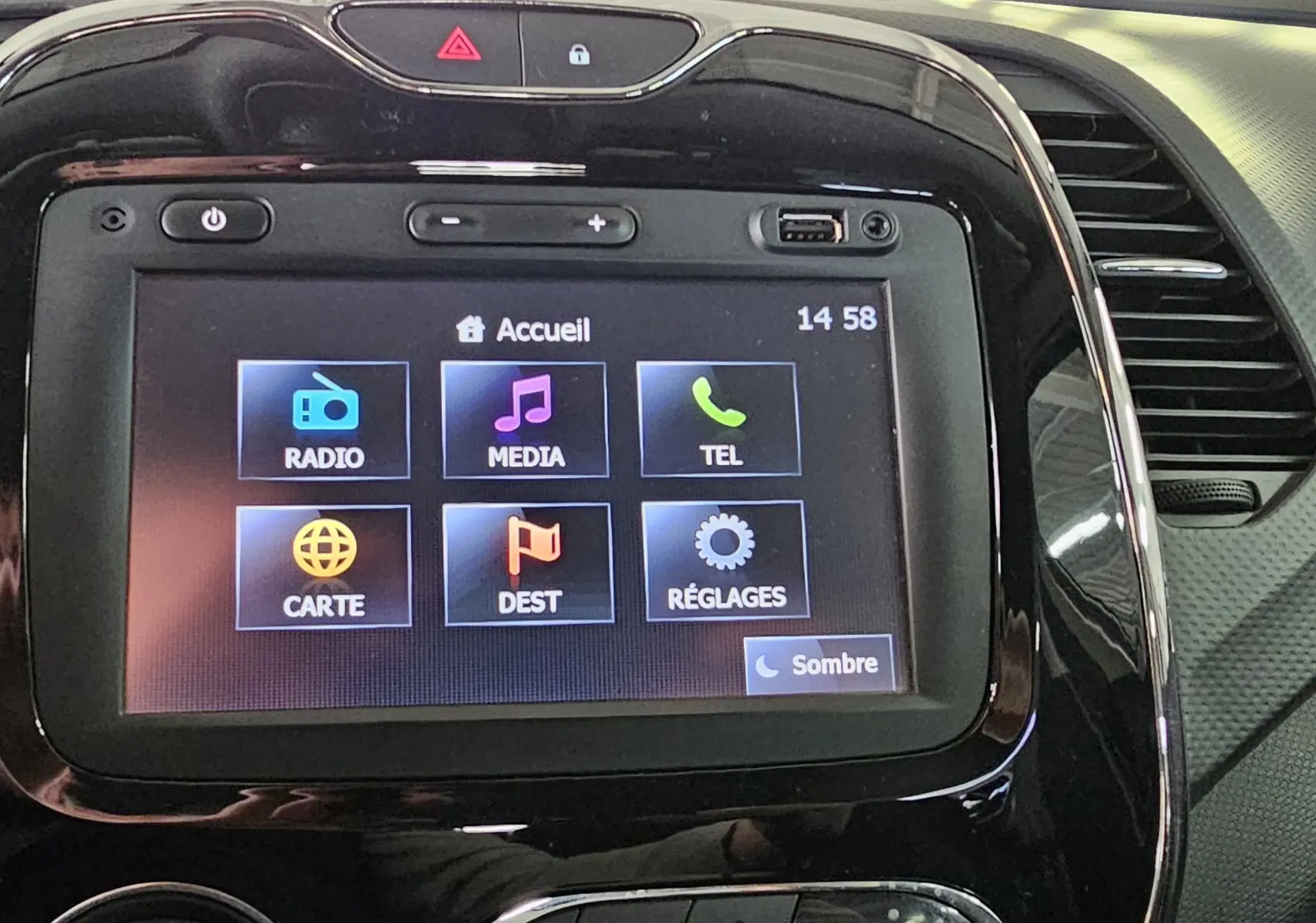 Écran tactile central du tableau de bord du Renault Captur gris, avec interface multimédia affichant radio, média et navigation.