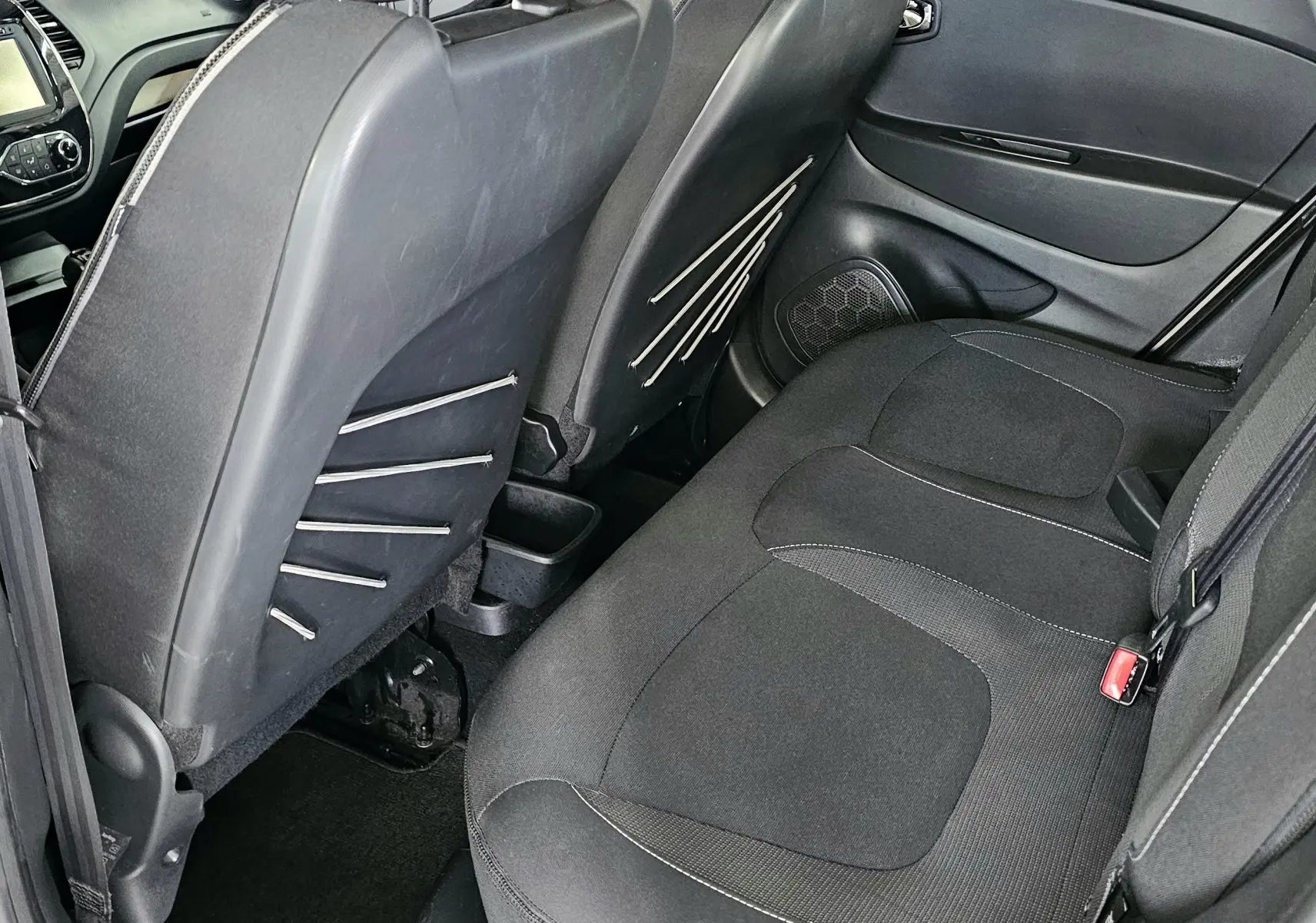 Vue intérieure arrière côté droit du Renault Captur gris 2014, montrant les sièges arrière et le dos des sièges avant.