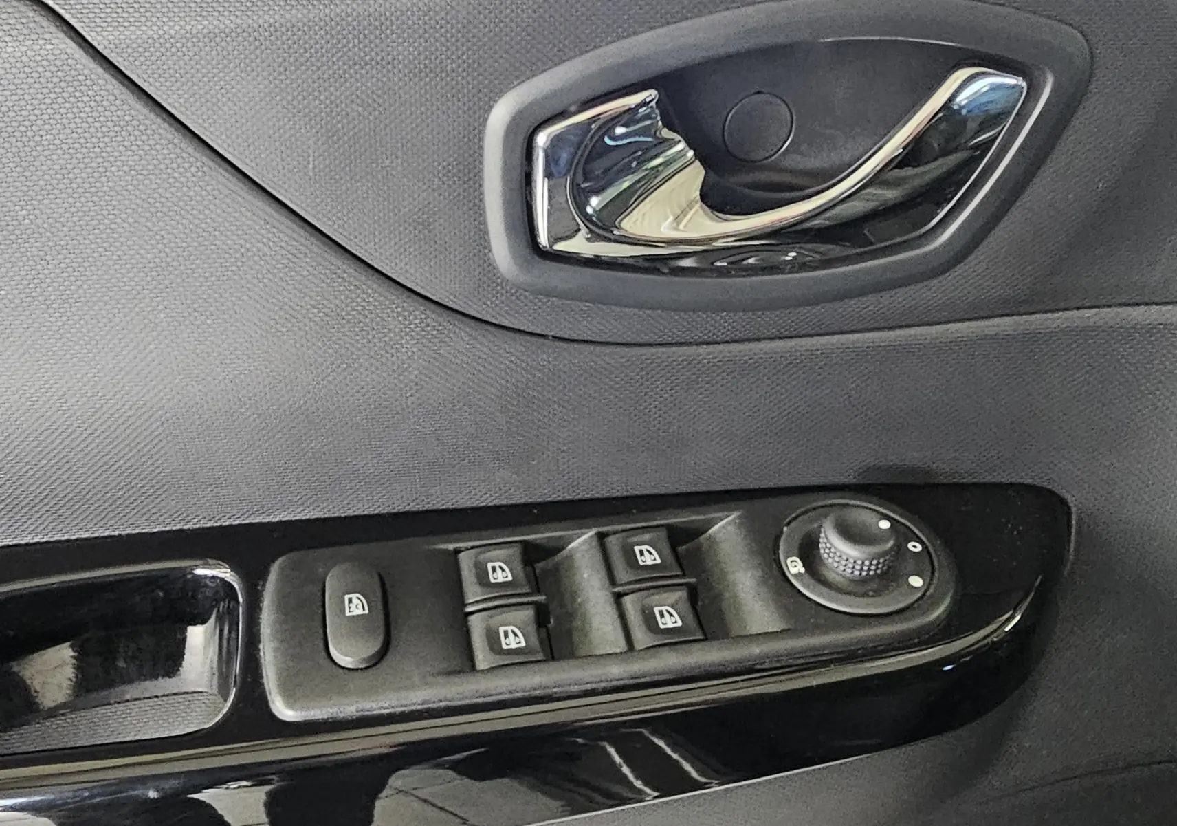 Gros plan sur la commande des vitres électriques et la poignée intérieure côté conducteur du Renault Captur gris 2014.