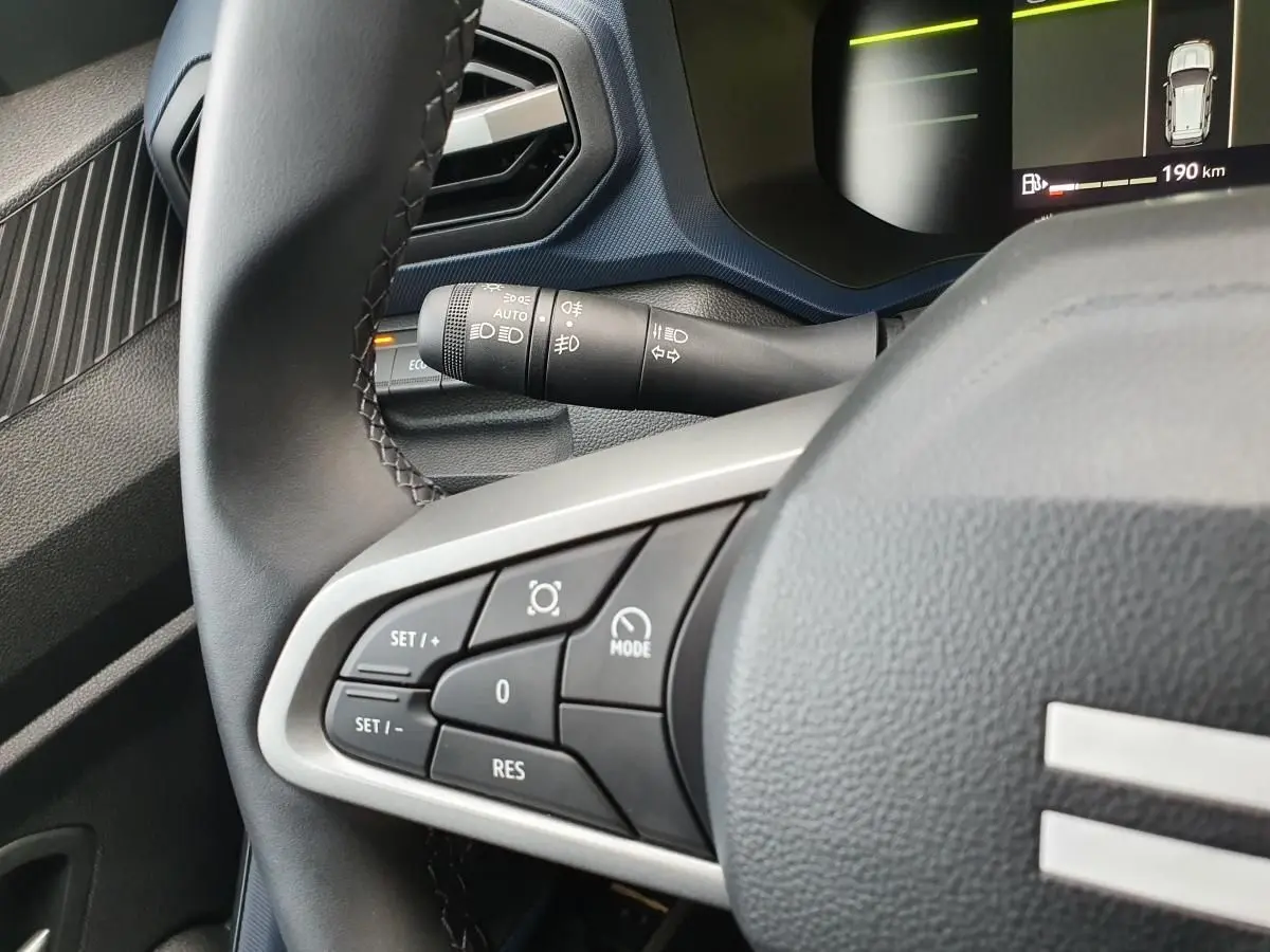 Gros plan sur les commandes au volant du Dacia Duster 2025, intérieur noir avec affichage numérique partiel.