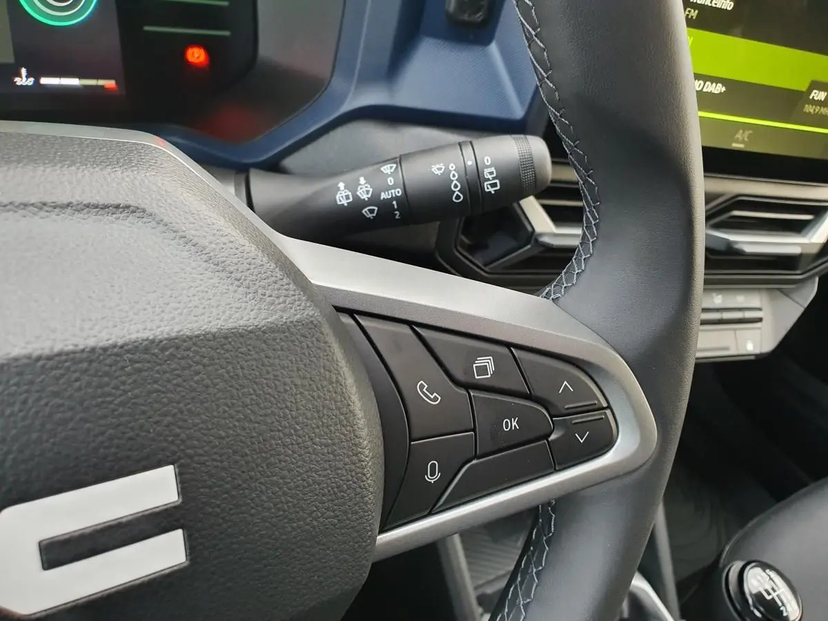 Gros plan sur le volant noir du Dacia Duster 2025, côté droit, avec commandes intégrées et tableau de bord partiellement visible.