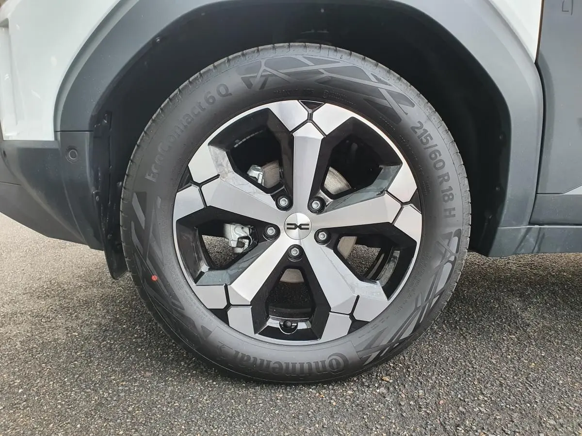 Gros plan sur la jante alliage 18” diamantée Tagasan du côté gauche du Dacia Duster blanc glacier 2025.