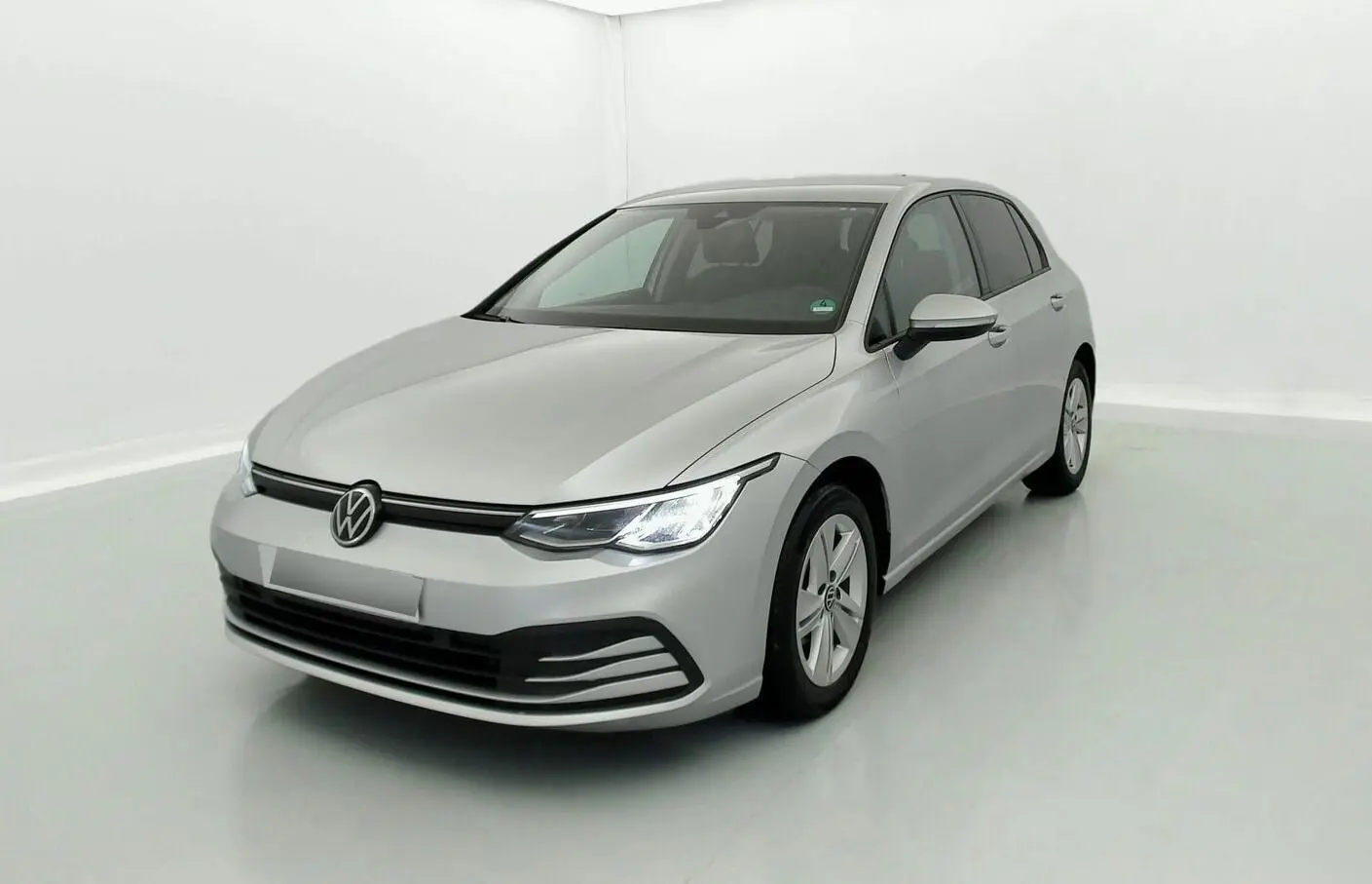 Volkswagen Golf VIII gris reflex vue 3/4 avant droit avec phares allumés dans un studio blanc.