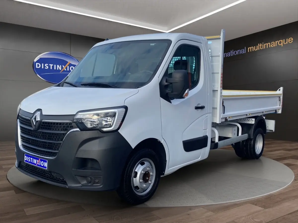 Renault Master blanc en 3/4 avant droit, benne arrière ouverte, calandre noire et jantes acier visibles.