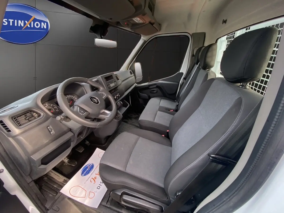 Vue intérieure côté conducteur du Renault Master 2024 blanc, montrant le tableau de bord et les sièges gris.