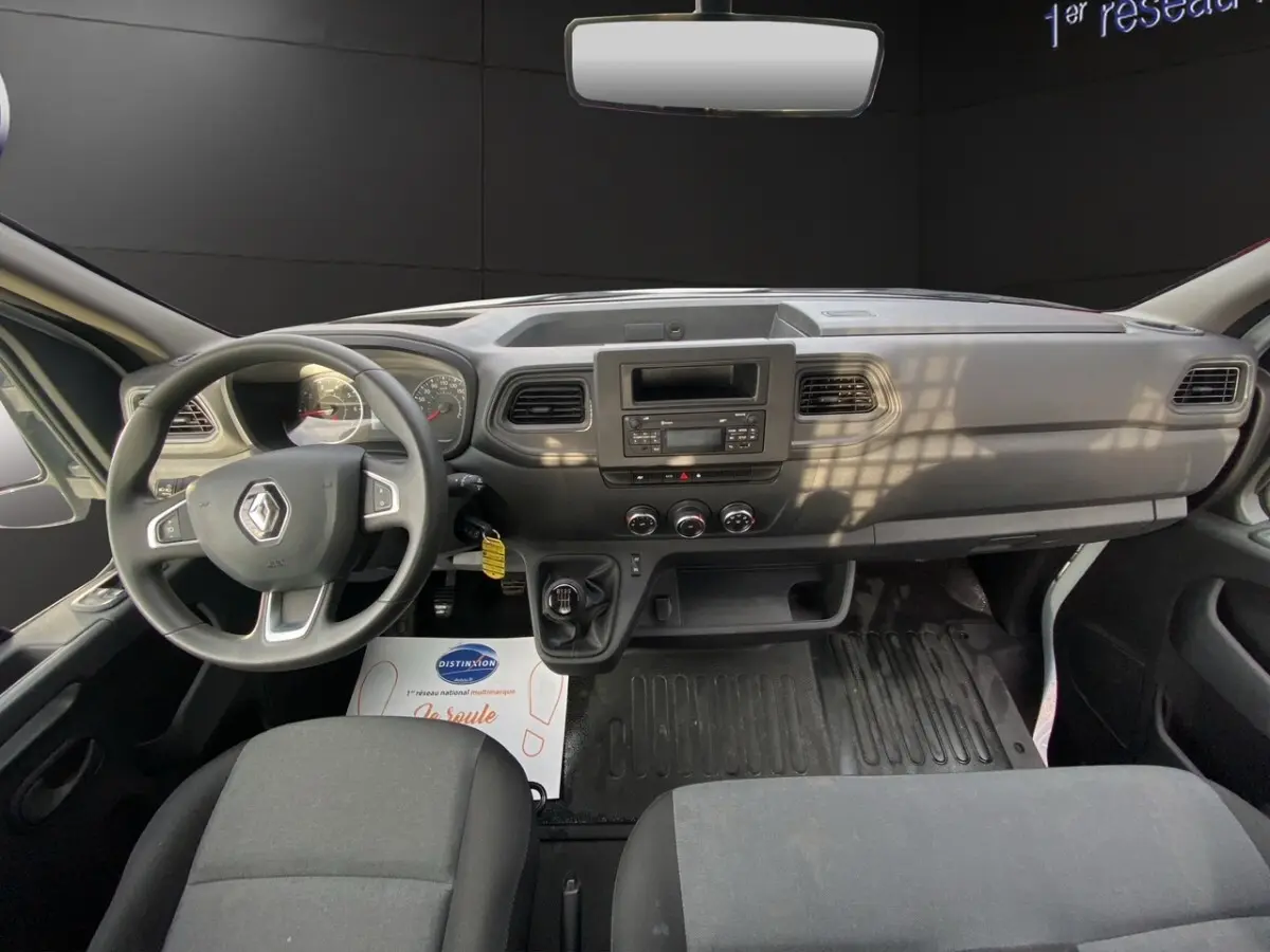 Vue intérieure avant du Renault Master 2024 blanc, tableau de bord simple avec volant multifonction et boîte manuelle.