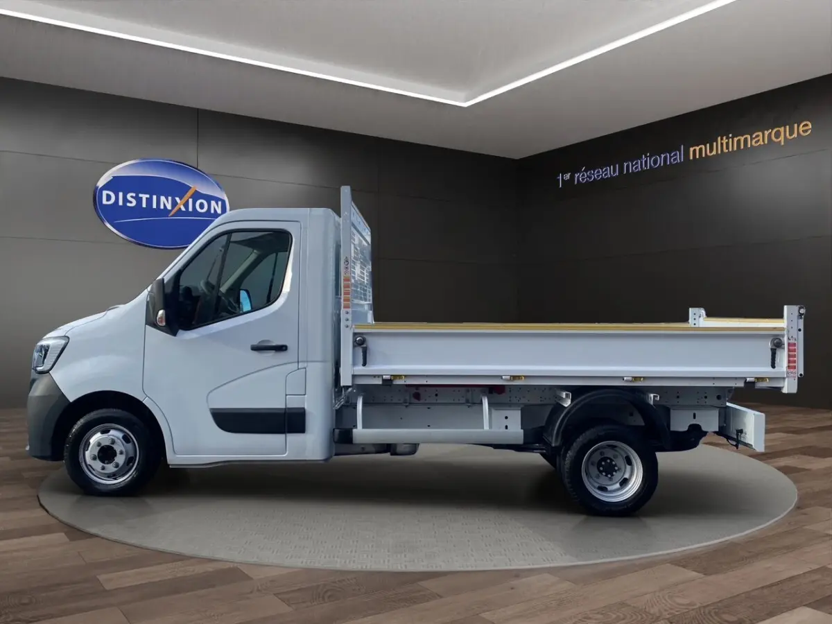 Profil droit d’un Renault Master blanc 2024 avec benne arrière, présenté en intérieur sur fond sombre.