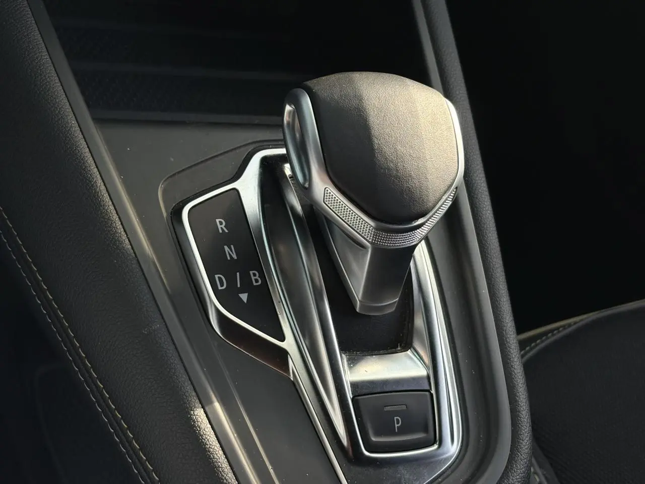 Le levier de vitesse e-shifter de la Renault SYMBIOZ E-Tech Full Hybrid, vue rapprochée du console centrale noire.