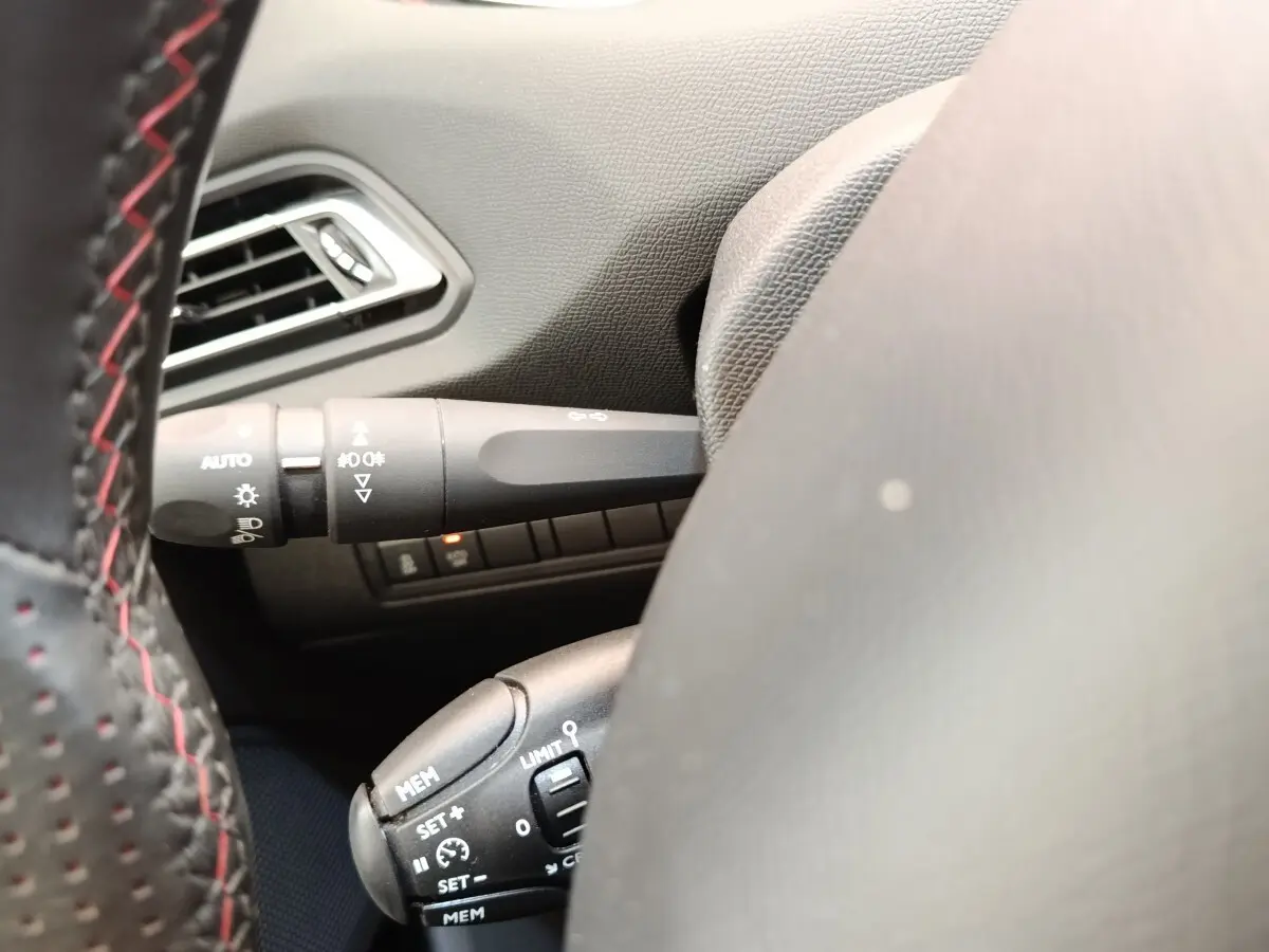 Gros plan sur le volant cuir noir avec coutures rouges et commandes de régulateur de vitesse sur Peugeot 308 GT Line 2016.