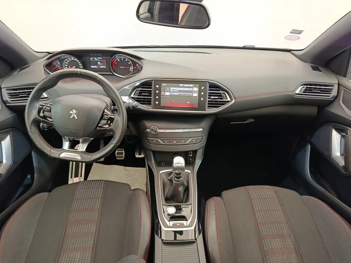 Vue intérieure avant de la Peugeot 308 GT Line 2016, volant cuir multifonctions et écran tactile central noir.