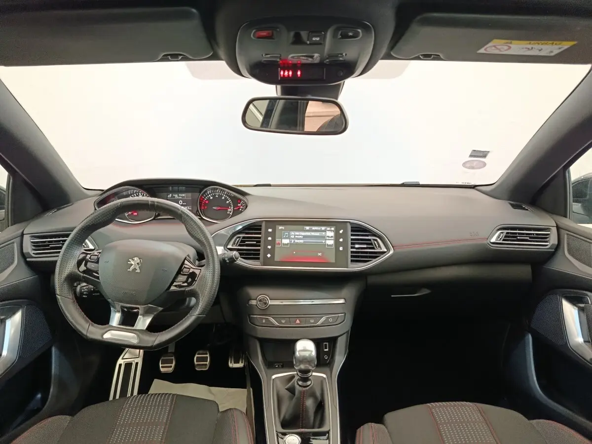 Vue intérieure avant de la Peugeot 308 GT Line 2016, tableau de bord noir avec volant cuir multifonctions et écran tactile central.