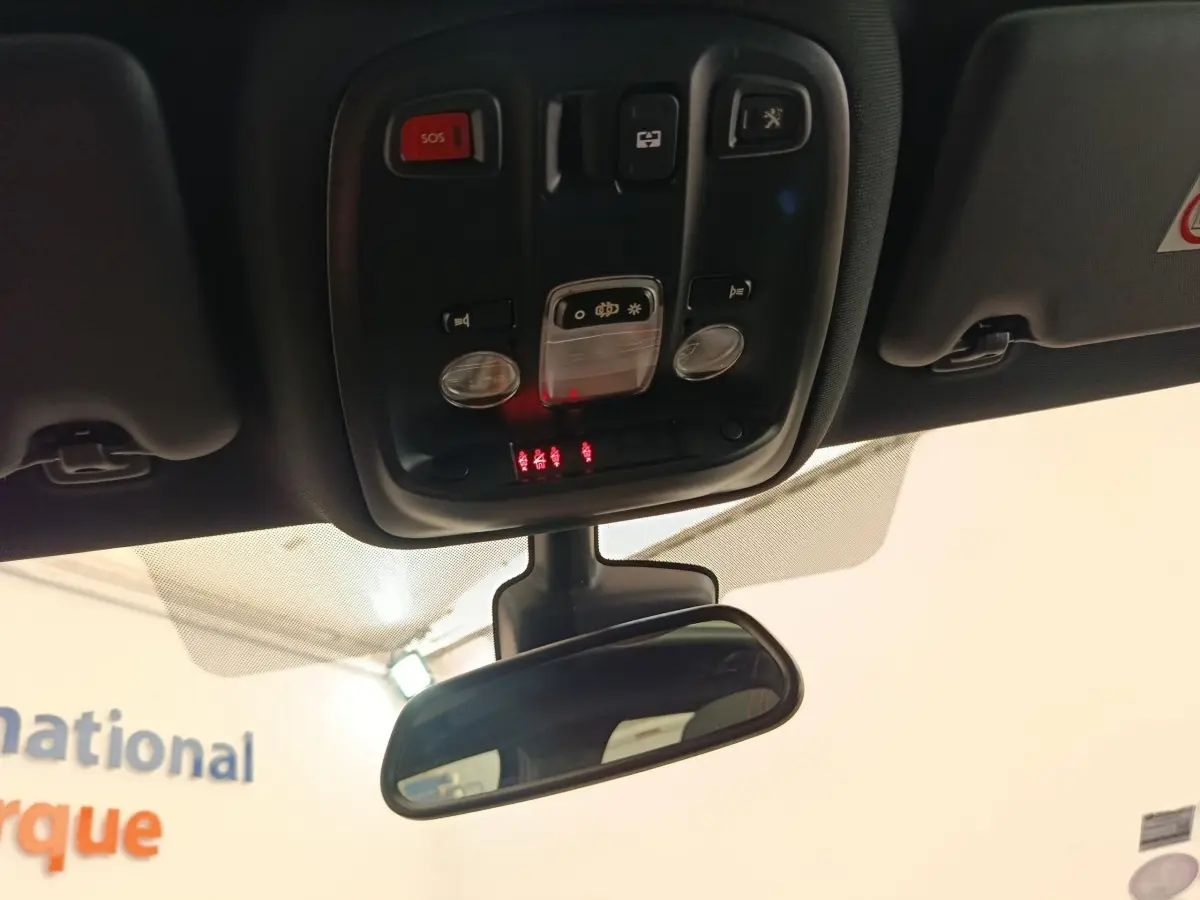 Vue en contre-plongée du plafonnier et du rétroviseur intérieur d'une Peugeot 308 noire de 2016.