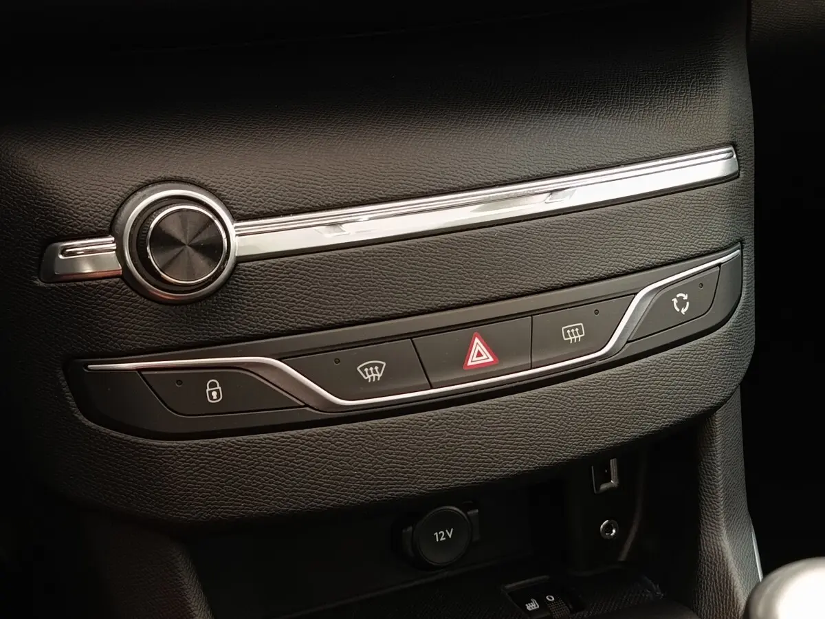 Vue rapprochée de la console centrale noire de la Peugeot 308 GT Line 2016 avec commandes de verrouillage, hazard et climatisation.