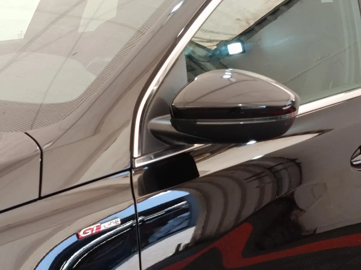 Gros plan sur le rétroviseur droit et l’emblème GT Line d’une Peugeot 308 noire, vue côté droit.