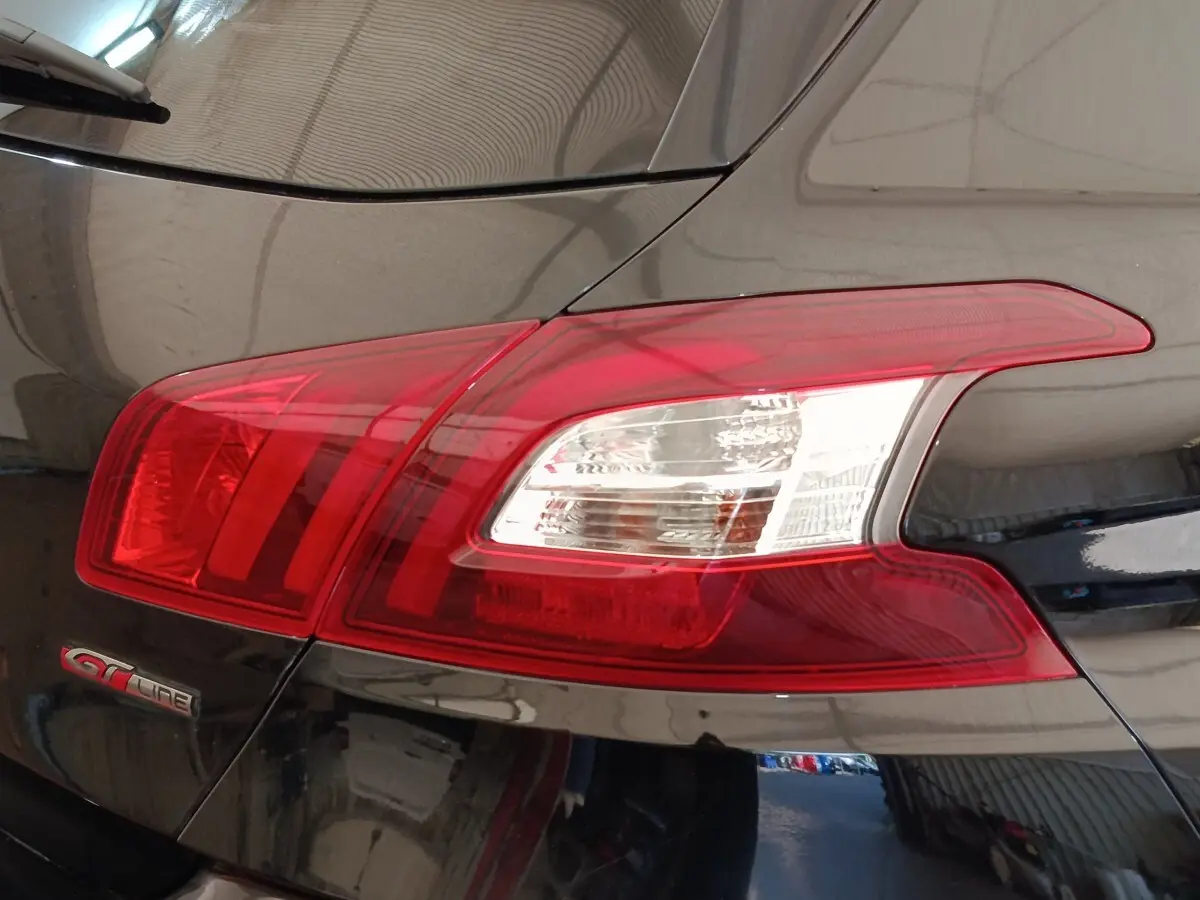Gros plan sur le feu arrière droit rouge et blanc d’une Peugeot 308 GT Line noire de 2016.