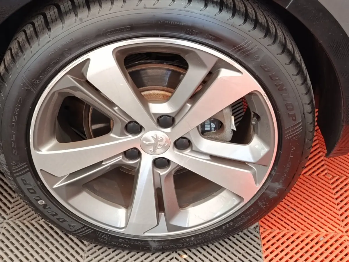 Gros plan sur la jante alliage argentée et le pneu Dunlop d'une Peugeot 308 noire, vue côté droit.