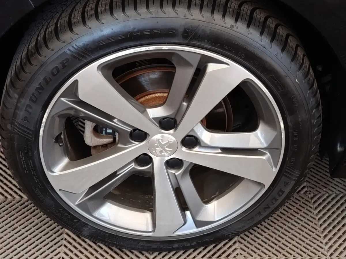 Gros plan sur la jante alliage argentée et pneu Dunlop d'une Peugeot 308 noire de 2016.