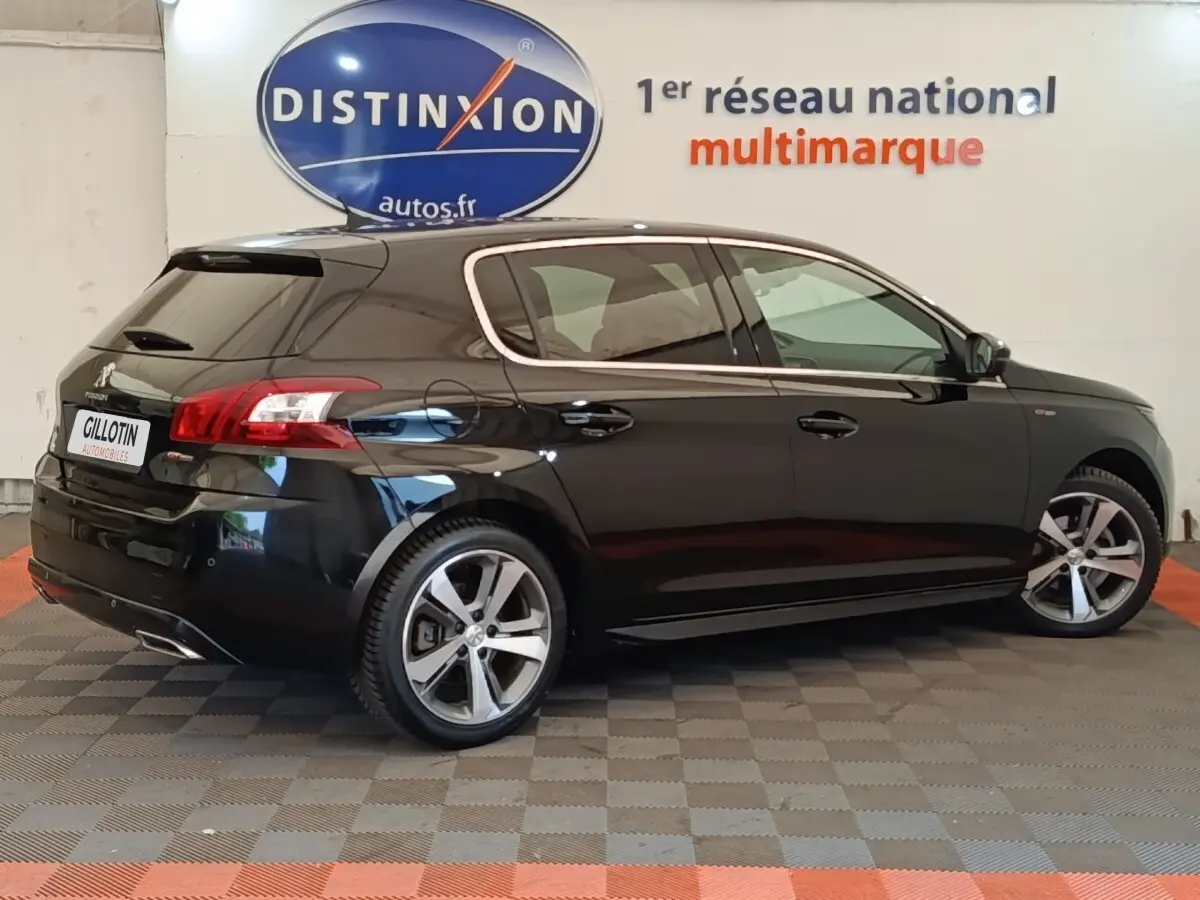 Peugeot 308 noir vue de profil droit en intérieur, avec jantes alliage et feux arrière distinctifs.