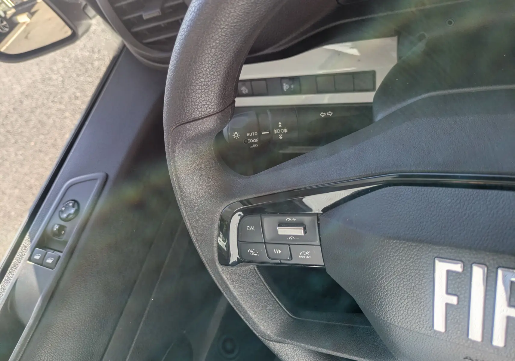 Vue rapprochée du volant et de la portière côté gauche du FIAT Scudo Fourgon blanc, avec commandes intégrées au volant.