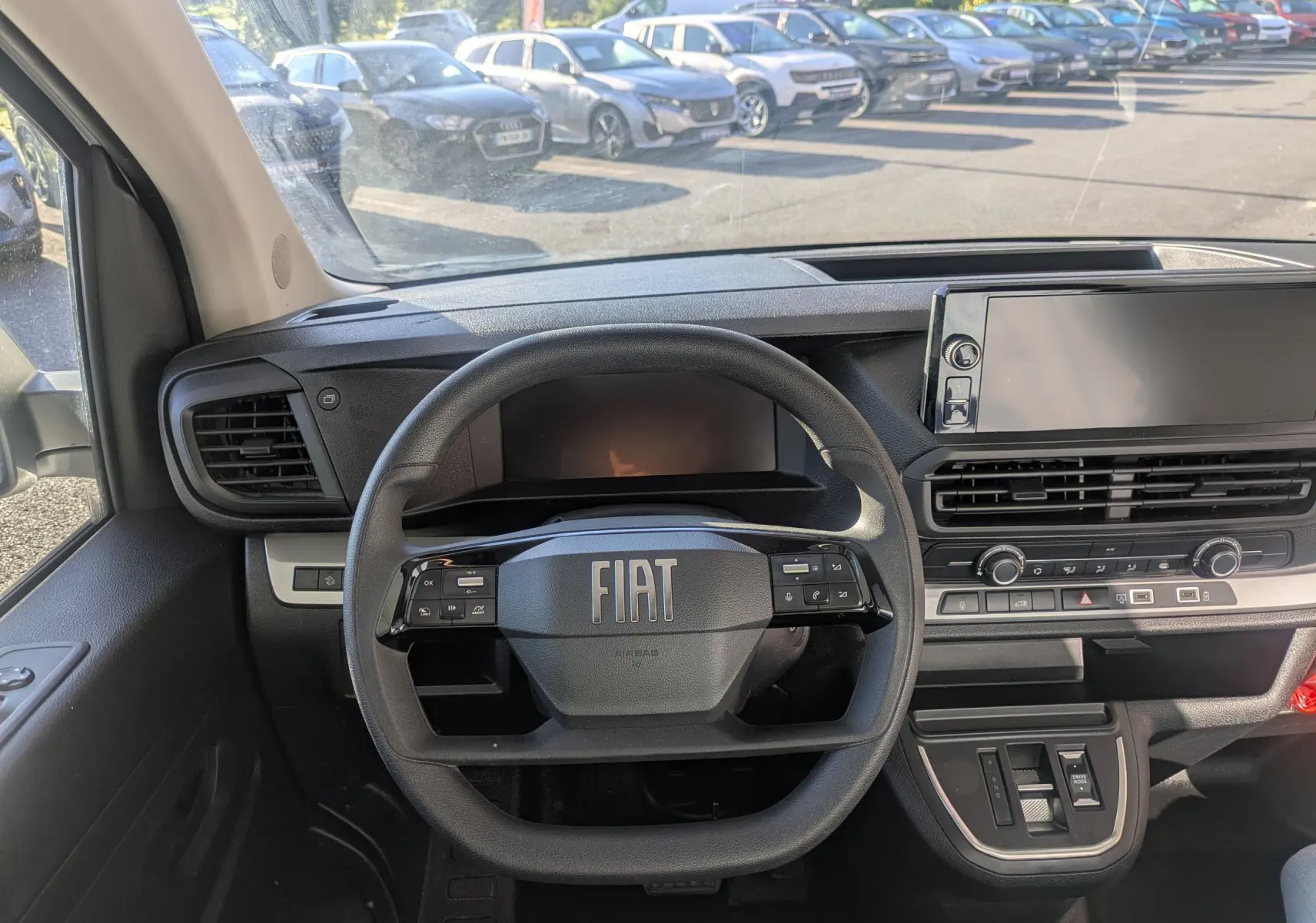 Vue intérieure centrée sur le volant FIAT et le tableau de bord avec écran tactile large du Fiat Scudo Fourgon blanc.