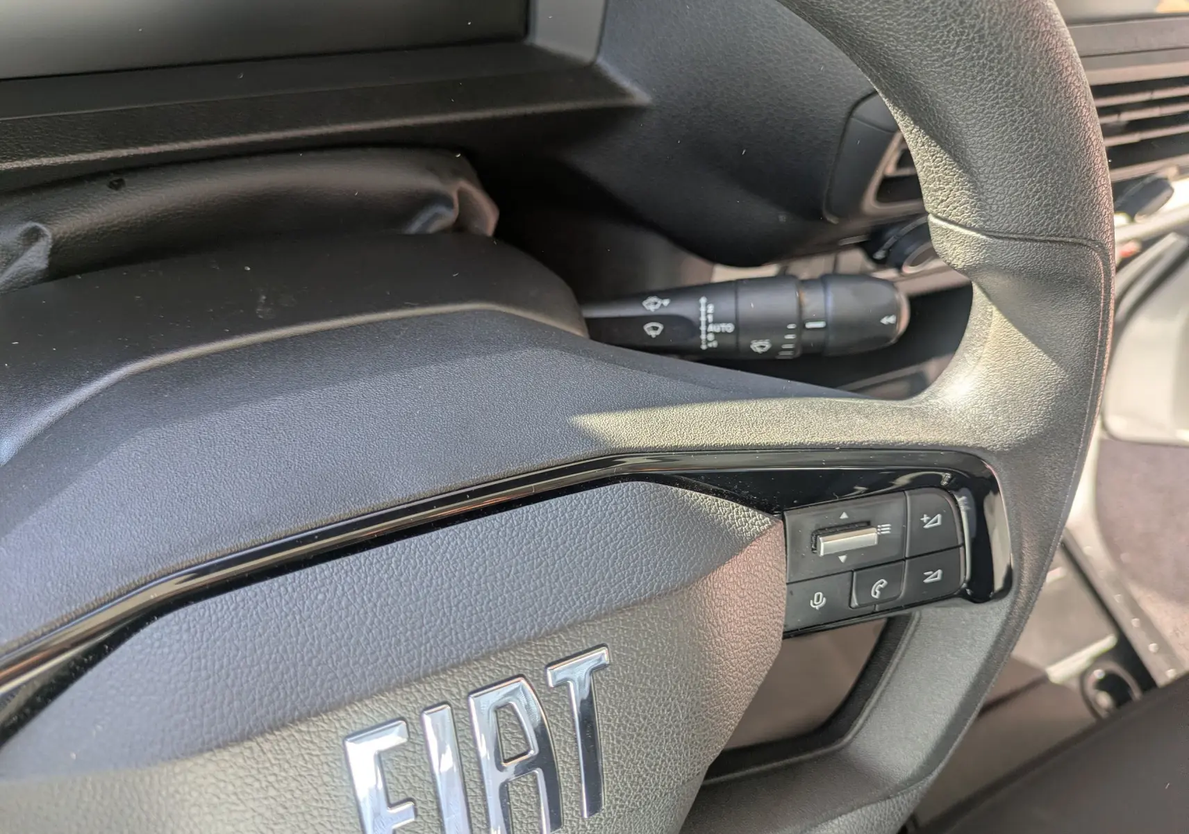Gros plan sur le volant noir du Fiat Scudo Fourgon 2025 avec commandes intégrées et logo FIAT visible.