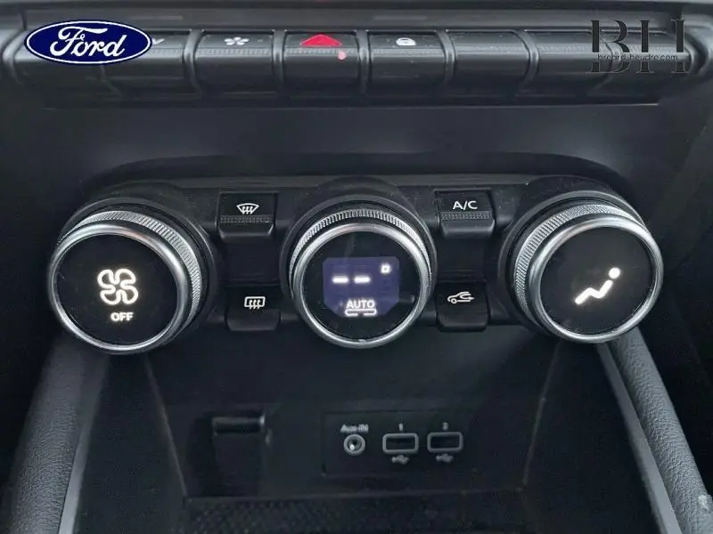 Panneau de commande de climatisation avec trois boutons rotatifs et prises USB en bas, intérieur noir.