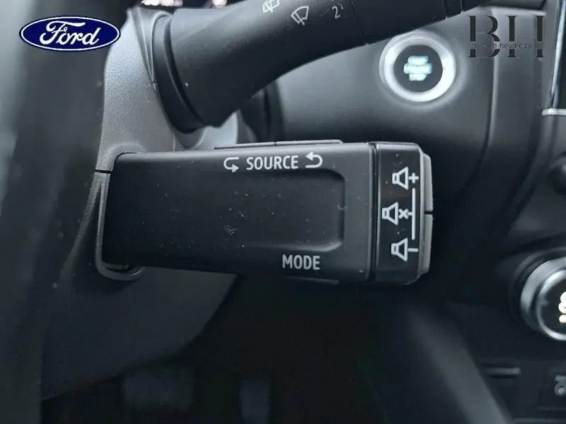 Gros plan sur la commande au volant noire du Renault Captur 1.6 E-Tech hybride rechargeable, intérieur gris Highland/Noir Etoile.