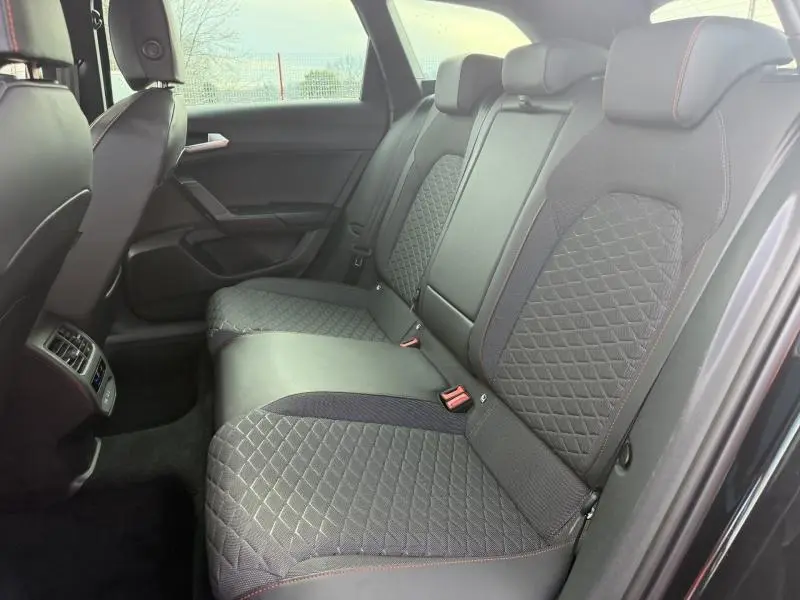 Vue intérieure côté droit des sièges arrière en tissu noir avec surpiqûres rouges du SEAT LEON ST 1.5 eTSI Hybrid 2025.