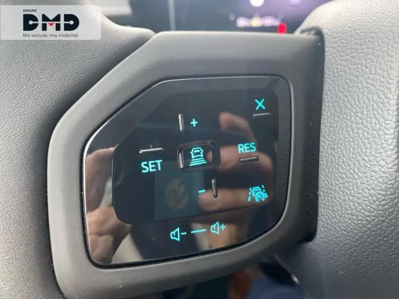 Gros plan sur les commandes au volant noir du Ford Explorer gris, avec réglages de vitesse et volume rétroéclairés en bleu.