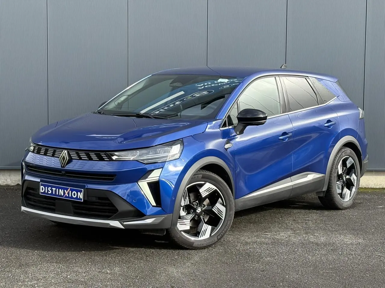 Renault Symbioz E-Tech bleu Iron, vue 3/4 avant droit, avec jantes 18 pouces et calandre distinctive noire.
