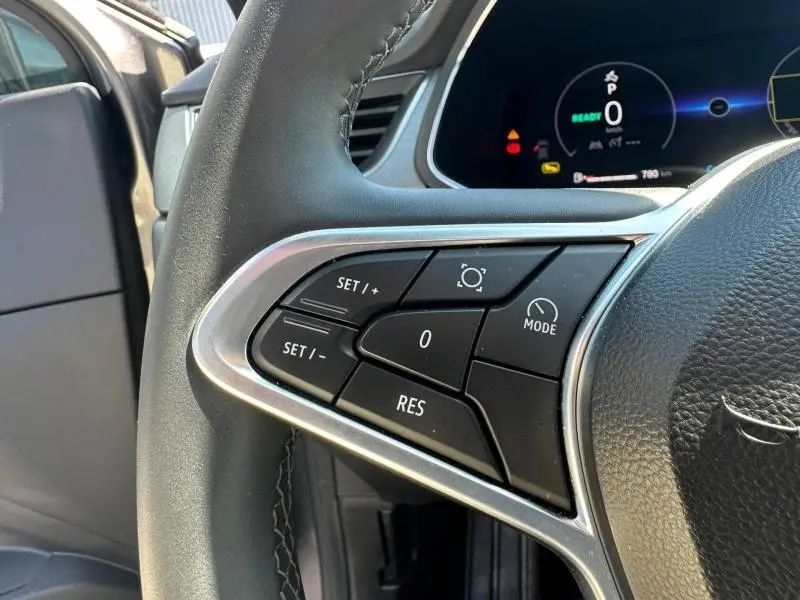 Gros plan sur les commandes au volant du Renault Captur 2025, finition Techno, avec tableau de bord numérique en arrière-plan.