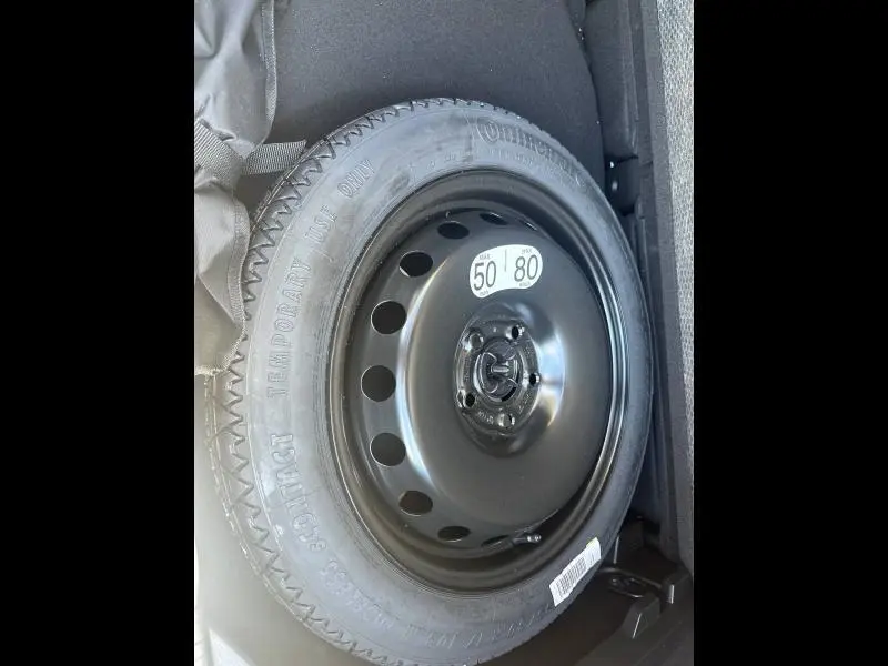Roue de secours noire en acier du Renault Captur 2025, visible dans le coffre sur fond gris.