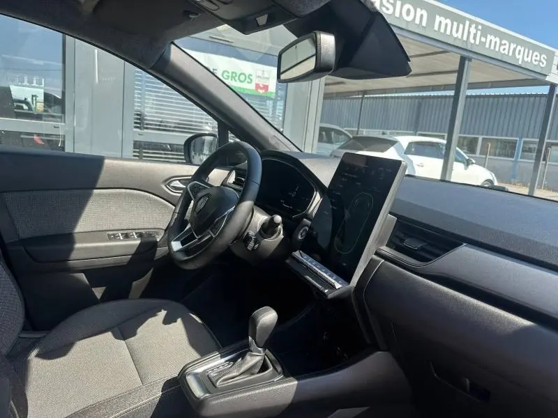 Vue intérieure côté conducteur du Renault Captur 1.6 E-Tech gris Cassiopée, avec écran tactile vertical et volant multifonction.