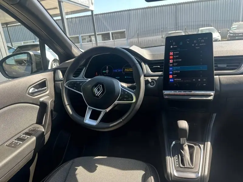 Vue intérieure avant du Renault Captur 2025, volant multifonction et écran tactile vertical central.