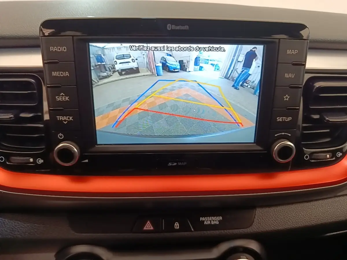 Écran tactile central de la Kia Stonic 2019 affichant la caméra de recul avec guidage coloré, tableau de bord noir et orange.