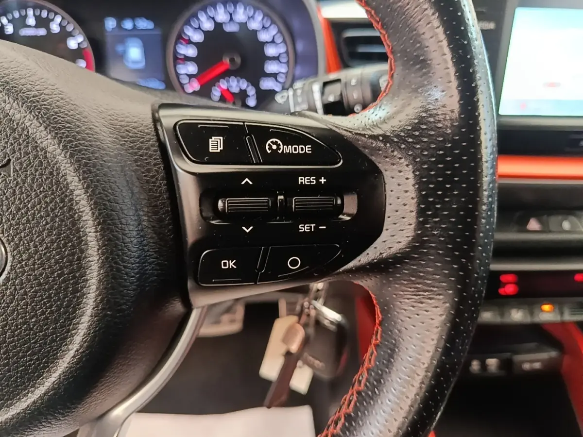 Gros plan sur le volant cuir perforé avec commandes multifonctions du Kia Stonic 2019, tableau de bord et écran tactile en arrière-plan.