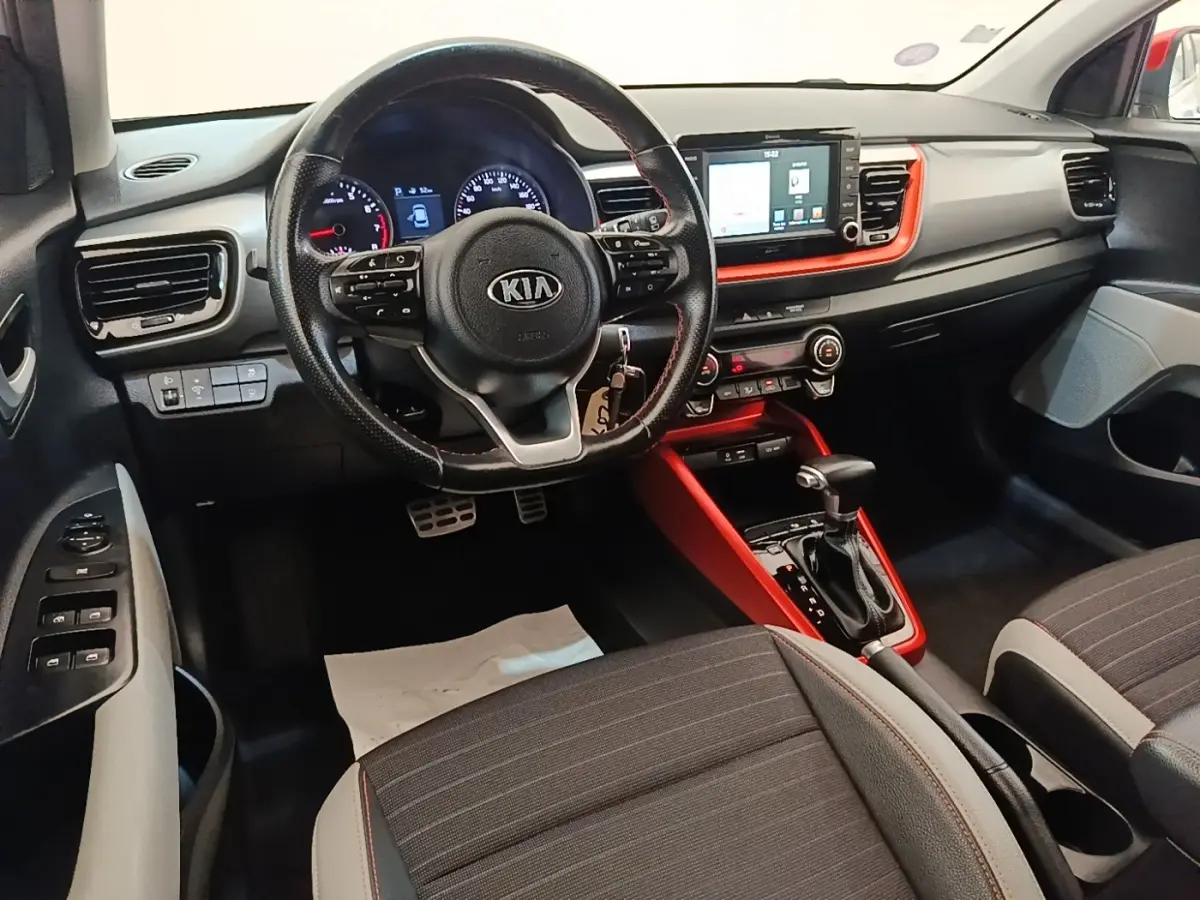 Intérieur avant du Kia Stonic gris clair, vue centrée sur le volant multifonctions et la console tactile rouge.