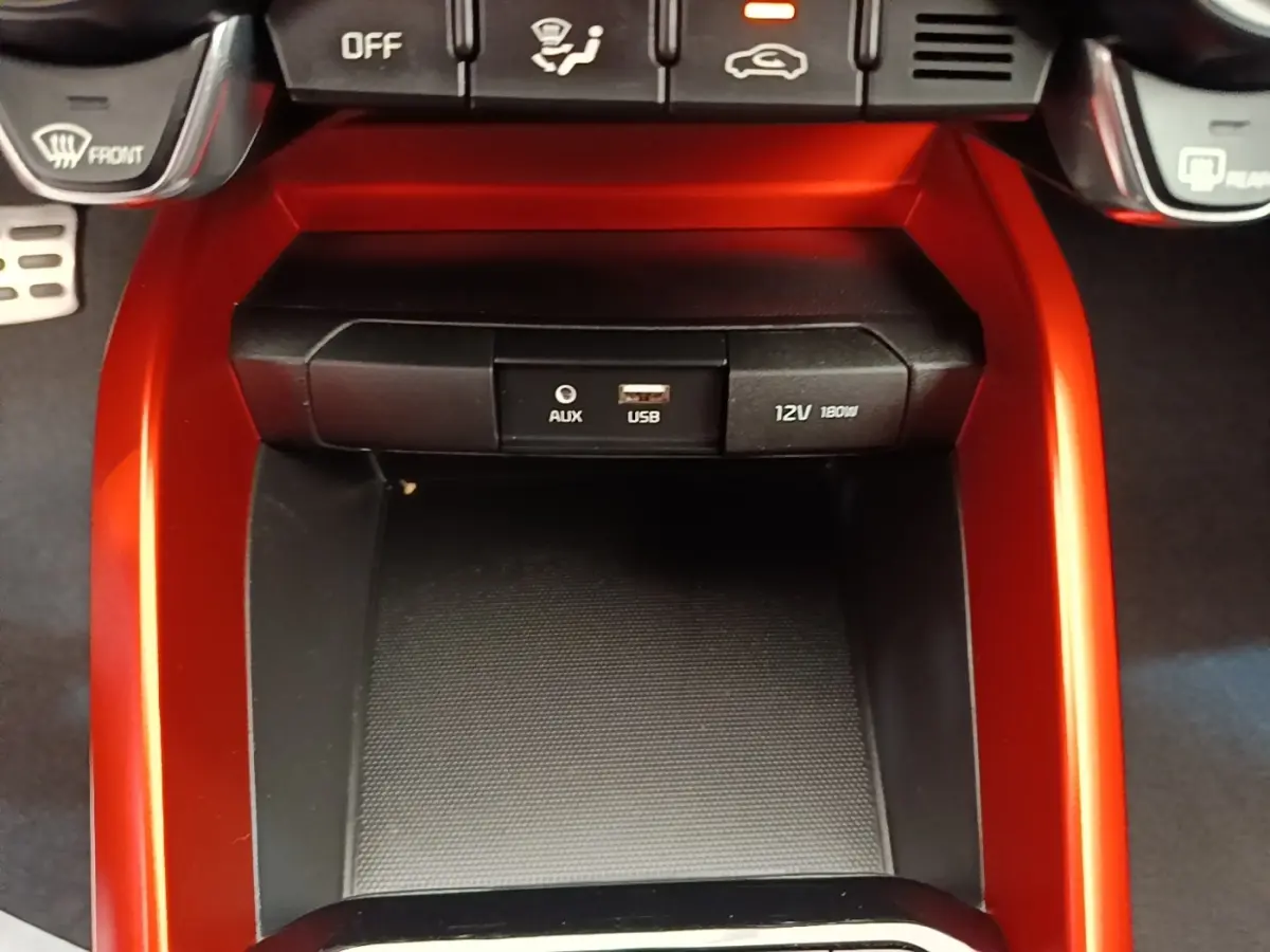 Gros plan sur la console centrale rouge du Kia Stonic 2019, avec prise AUX, USB et prise 12V visible.