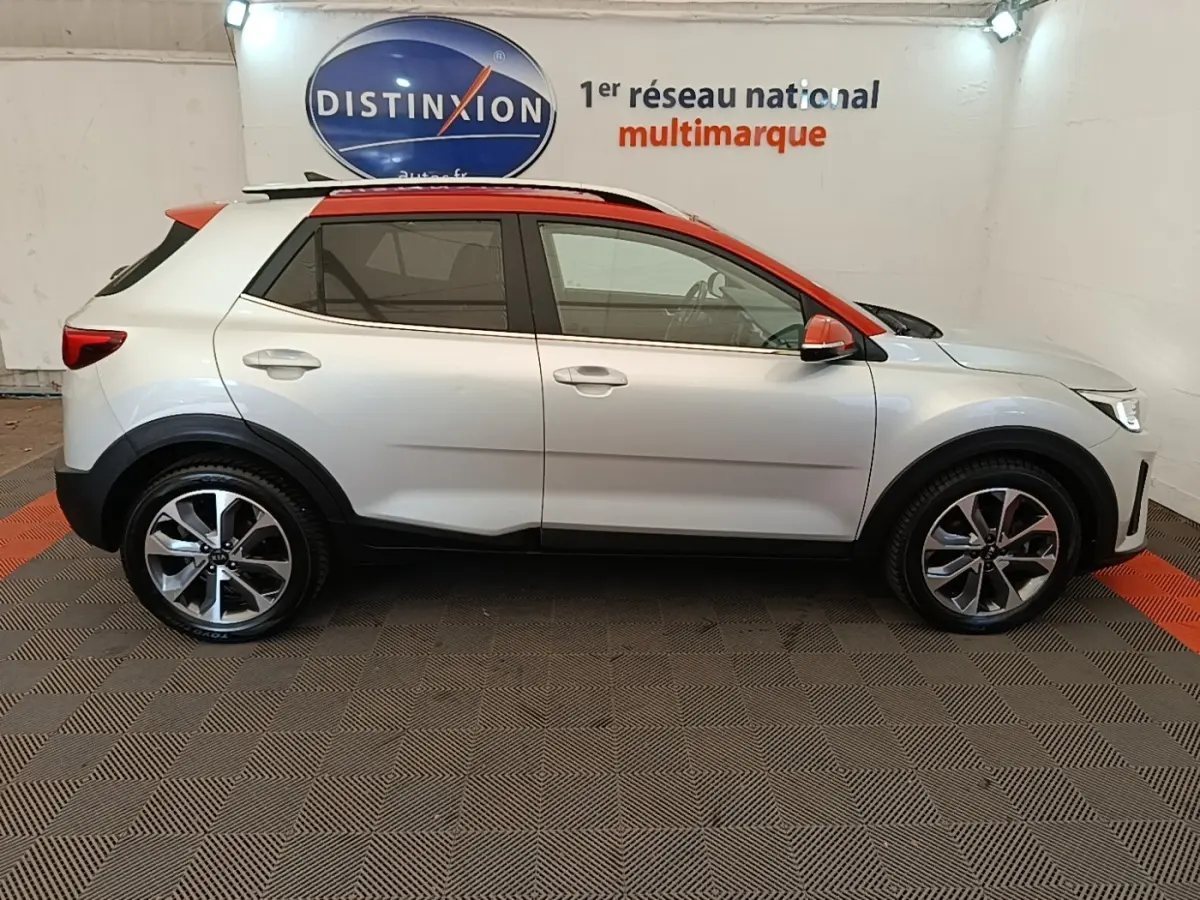 Vue de profil droit du KIA STONIC gris clair avec toit et rétroviseurs orange, jantes alliage bicolores.