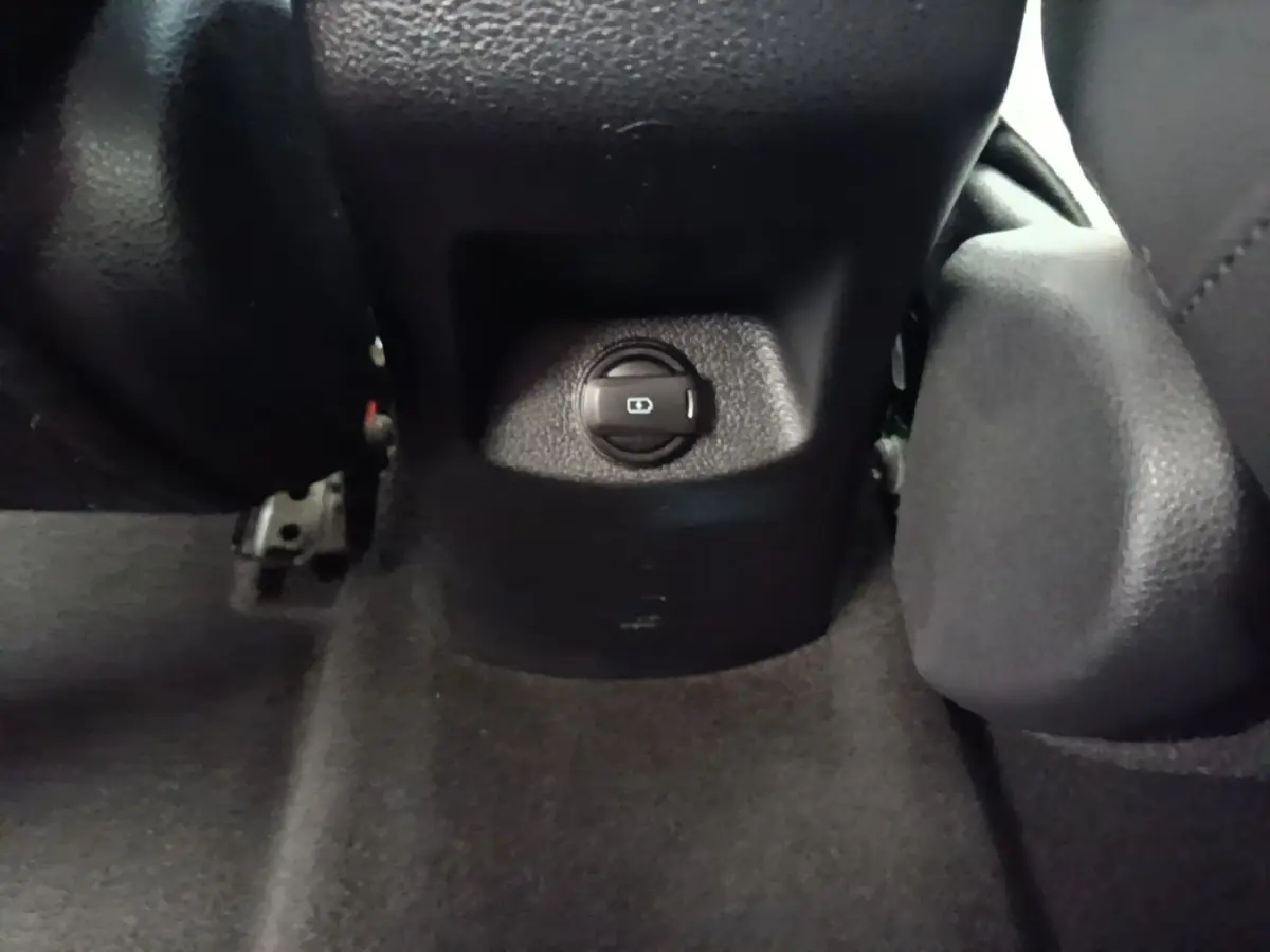 Gros plan sur le bouton de réglage centralisé des rétroviseurs dans l’habitacle noir du Kia Stonic gris clair.