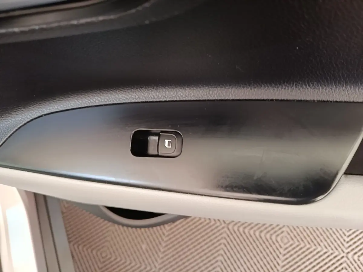Gros plan sur le bouton de verrouillage des portes côté conducteur dans l'habitacle du KIA Stonic gris clair.