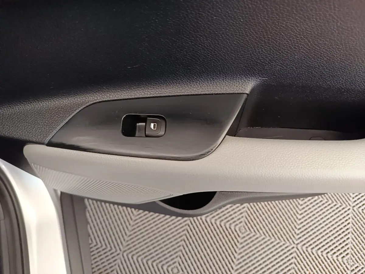 Détail de la poignée intérieure côté conducteur du KIA Stonic gris clair, avec bouton de verrouillage des portes.