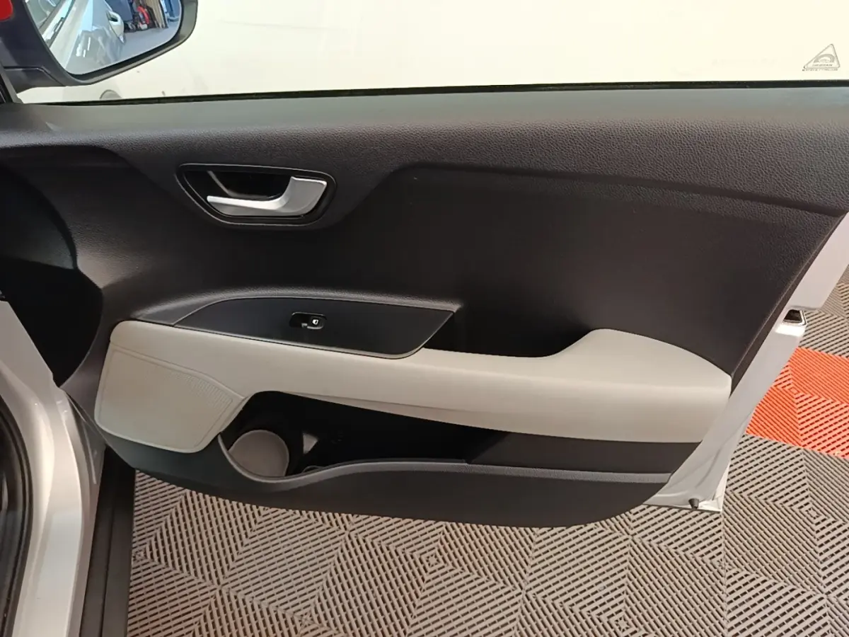 Vue intérieure du panneau de porte avant gauche gris clair et noir du Kia Stonic 2019 avec poignée argentée et rangement intégré.