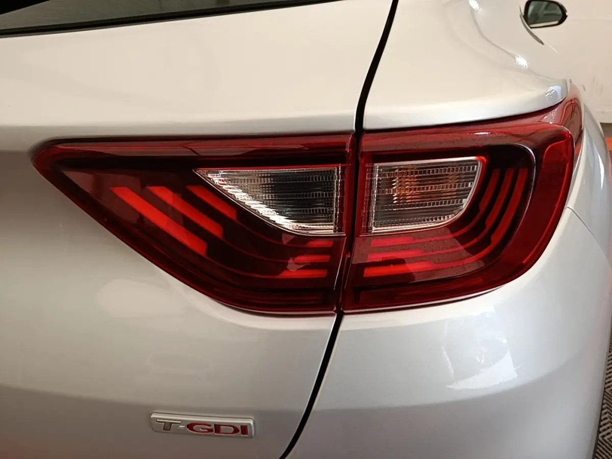 Gros plan sur le feu arrière droit rouge et blanc du KIA Stonic gris clair avec logo T-GDI visible.