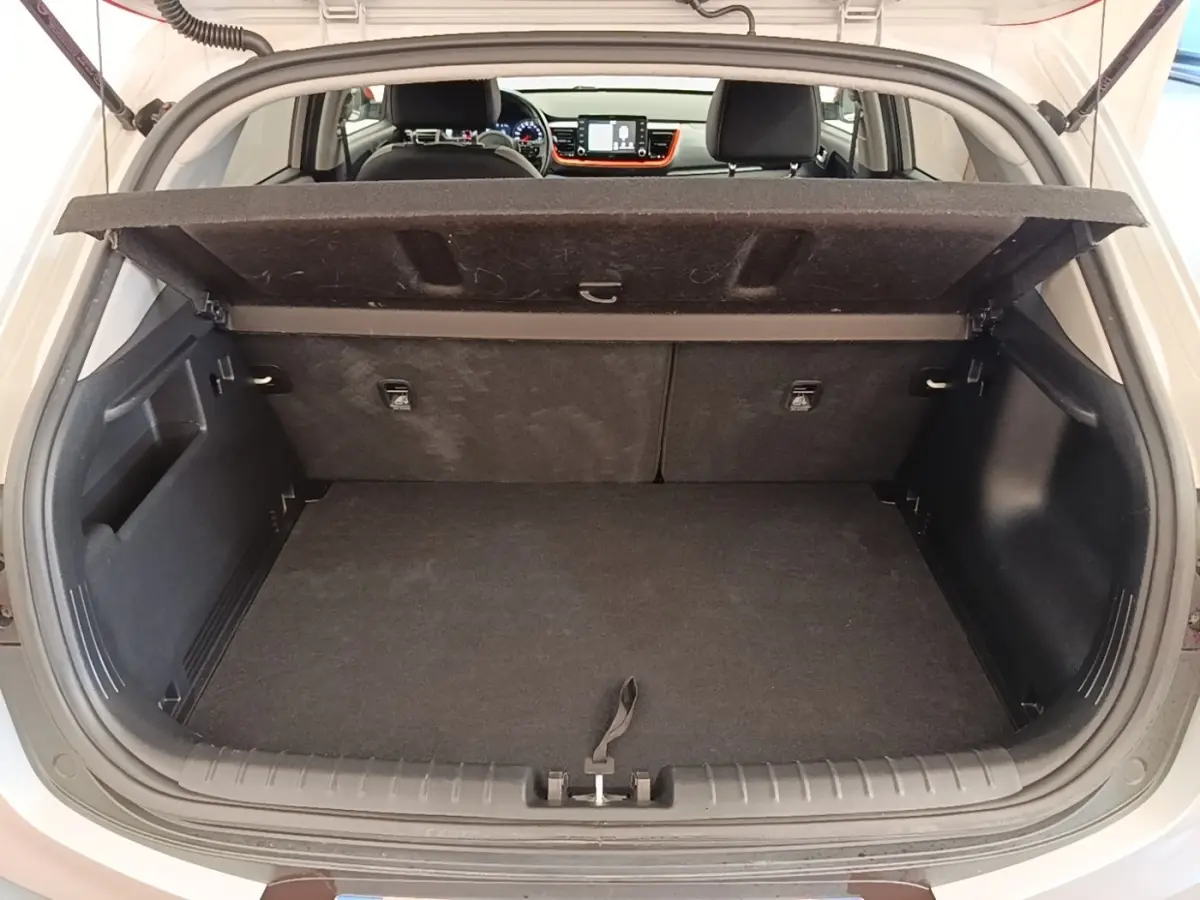 Vue arrière du coffre ouvert d'un KIA Stonic gris clair, avec intérieur noir et tablette de coffre relevée.