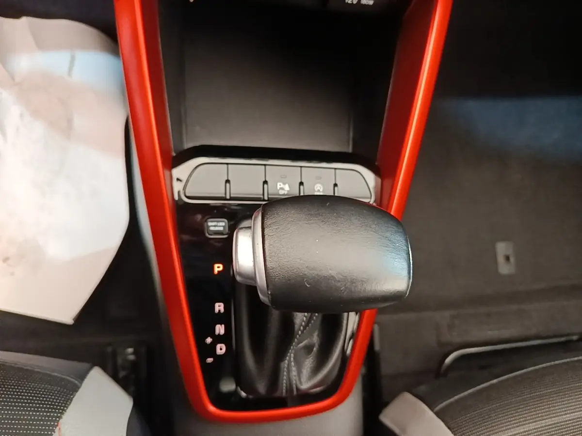 Le levier de vitesses automatique noir encadré d'un contour rouge dans l'habitacle d'une KIA STONIC gris clair.