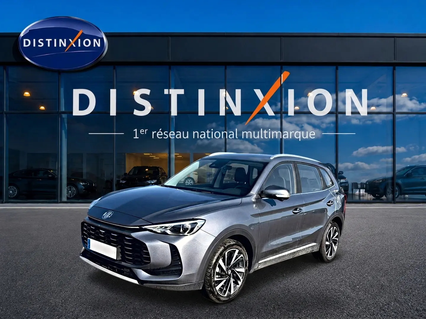 MG Motor ZS 1.5 hybrid gris vu en 3/4 avant droit devant une vitrine Distinxion.