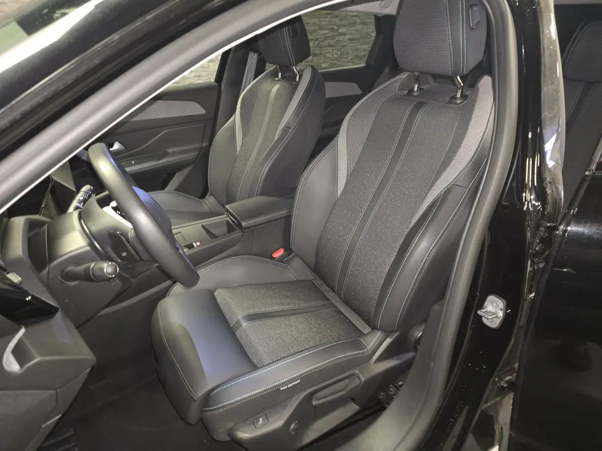 Intérieur Peugeot 308 SW noir, vue côté conducteur sur siège avant en tissu et cuir avec surpiqûres bleues.