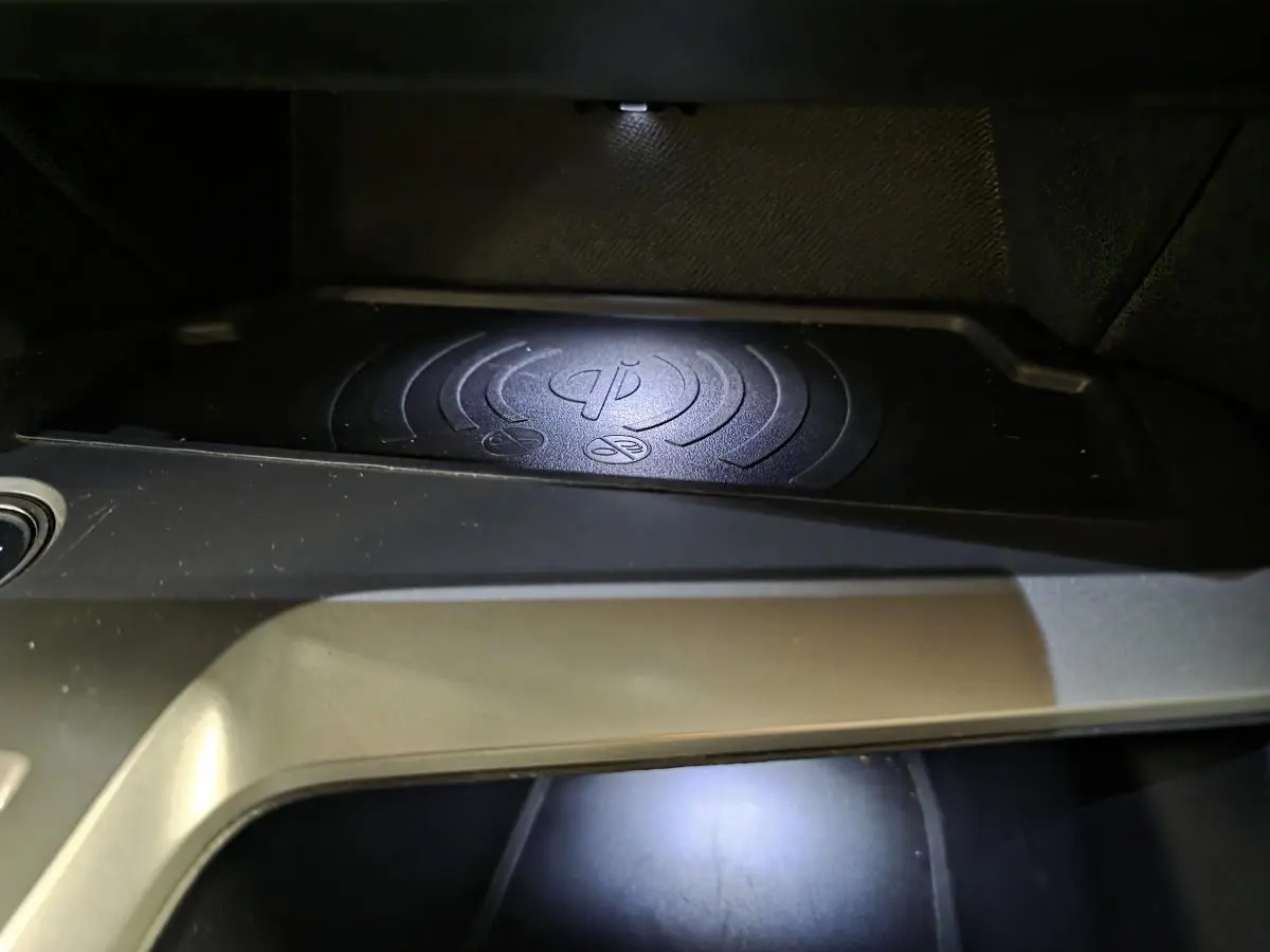 Gros plan sur le chargeur à induction noir intégré dans la console centrale de la Peugeot 308 SW 2024.