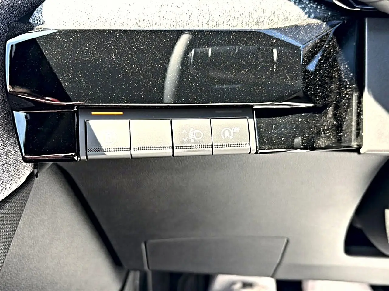 Gros plan sur les commandes sous le tableau de bord de la Renault Clio VI noire, avec finition brillante noire.